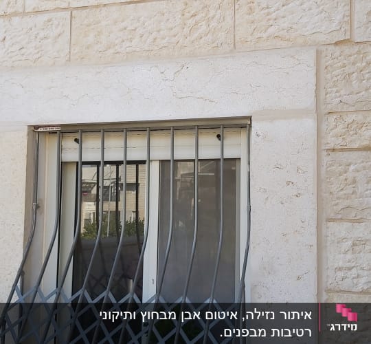 חלון עם סורגים על קיר אבן
